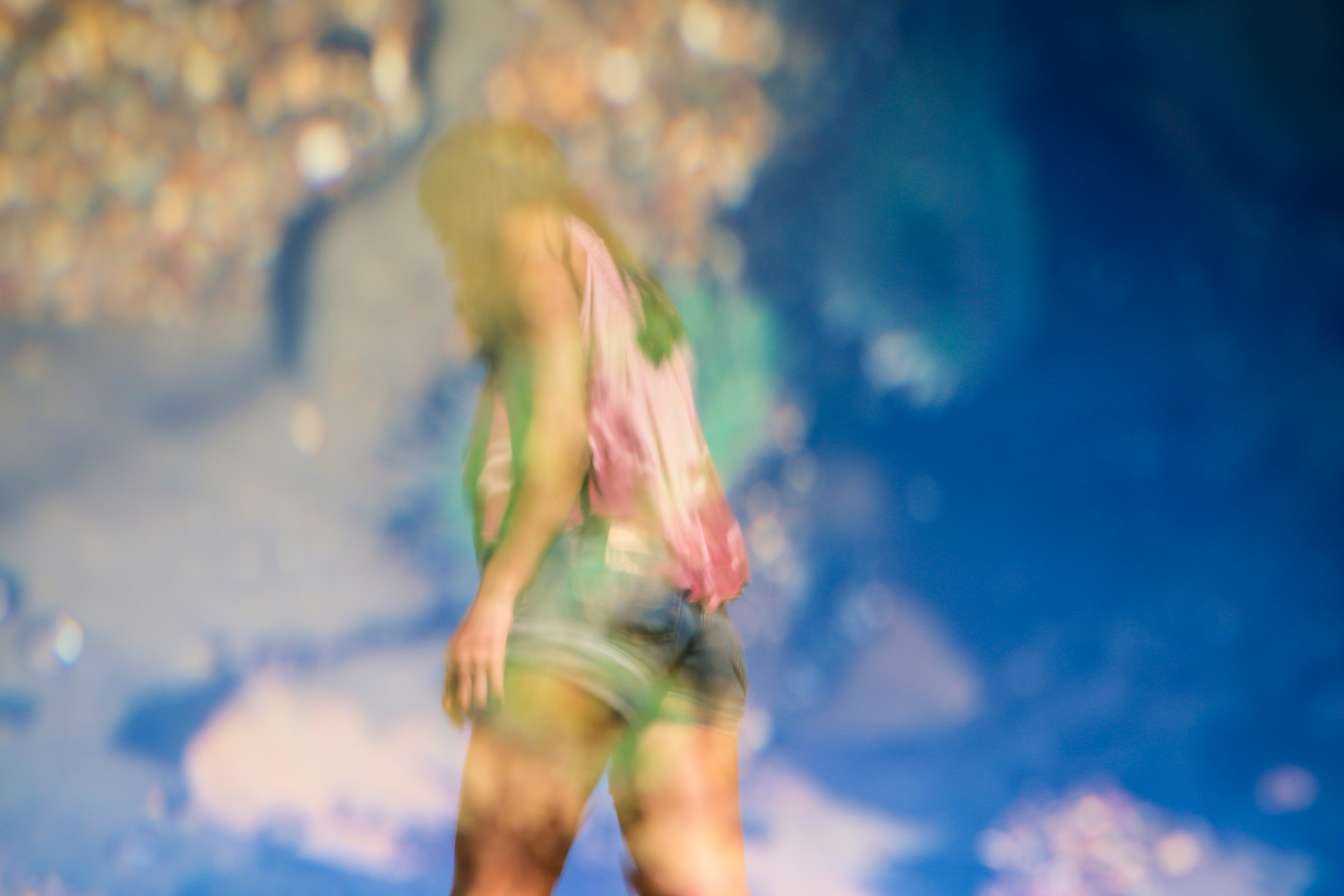 A blurry shot of a woman in shorts against a blue sky